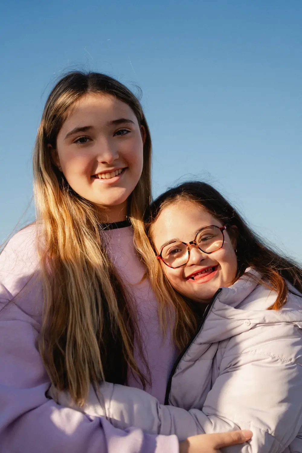 Two young girls are smiling into the camera.